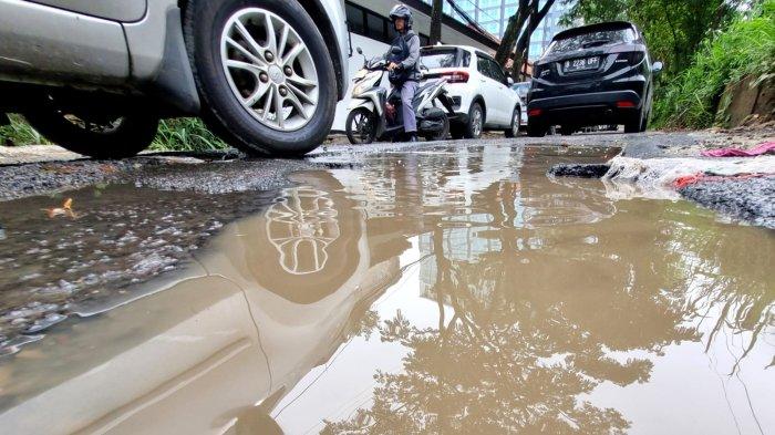 Pengguna jalan melintasi jalan rusak berlubang dan bak kontrol yang mengeluarkan air di Jalan Tera, Kelurahan Braga, Kecamatan Sumur Bandung, Kota Bandung, Jawa Barat, Jumat (7/2/2025).