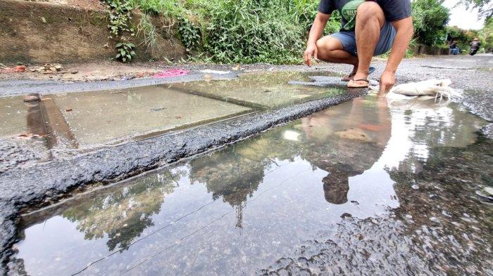 Budi Suryana (49) menutup jalan rusak berlubang dengan bongkaran tembok di samping bak kontrol yang mengeluarkan air di Jalan Tera, Kelurahan Braga, Kecamatan Sumur Bandung, Kota Bandung, Jawa Barat, Jumat (7/2/2025).
