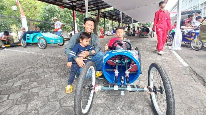 Salah seorang peserta muda, Averus datang bersama sang ayah, Fauzi mengikuti perlombaan kereta peti sabun di Jalan Diponegoro, Kota Bandung, Sabtu (26/8/2023).