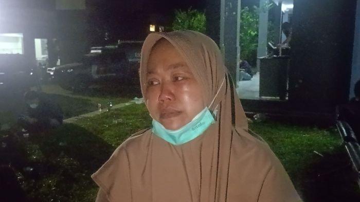 BERI KETERANGAN - Dede (38) ketika memberikan keterangan soal suaminya, Endang, yang tewas saat kegiatan pemusnahan amunisi kedaluwarsa di Pantai Cibalong, Kabupaten Garut, Senin (12/5/2025).