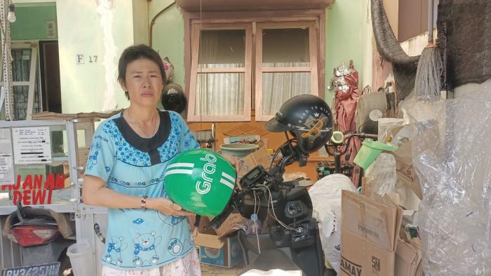 DRIVER OJOL JADI PEMULUNG -Driver ojol Rosdewi (40) sedang berdiri di samping sepeda motor miliknya dan kardus hasilnya memulung di Kota Jambi, Selasa (22/7/2025).