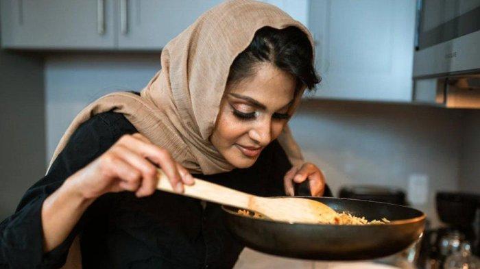 Ilustrasi seorang wanita menghangatkan makanan. Beirkut makanan yang sebaiknya tidak dipanaskan ulang untuk jadi menu sahur