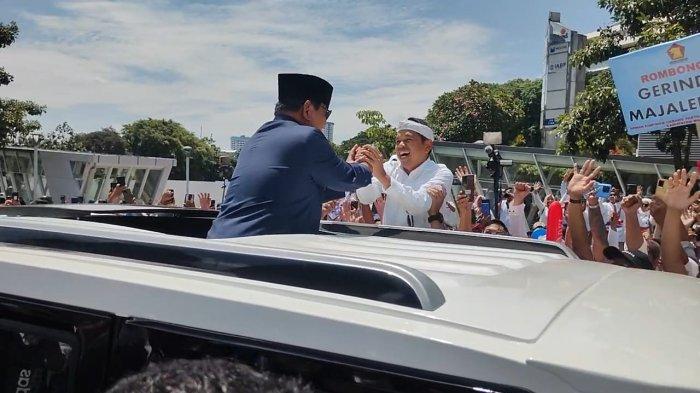 KDM yang memakai pakaian serba putih naik ke atas mobil dari arah depan menghampiri Prabowo yang berdiri di tengah mobil, Minggu (20/10/2024)