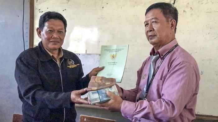 Kuasa hukum mantan kepsek yang membawa uang tabungan murid SDN Pakemitan 1 dan 3 (kanan) menitipkan uang ganti dari kliennya kepada Kades Pakemitan, Kecamatan Ciawi, Kabupaten Tasikmalaya, Jawa Barat, Senin (31/7/2023).