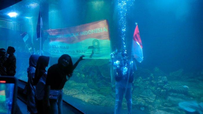 Pengunjung mengabadikan momen pengibaran bendera Merah Putih di dalam akuarium terpanjang di Indonesia di Kabupaten Pangandaran, Kamis (17/8/2023)