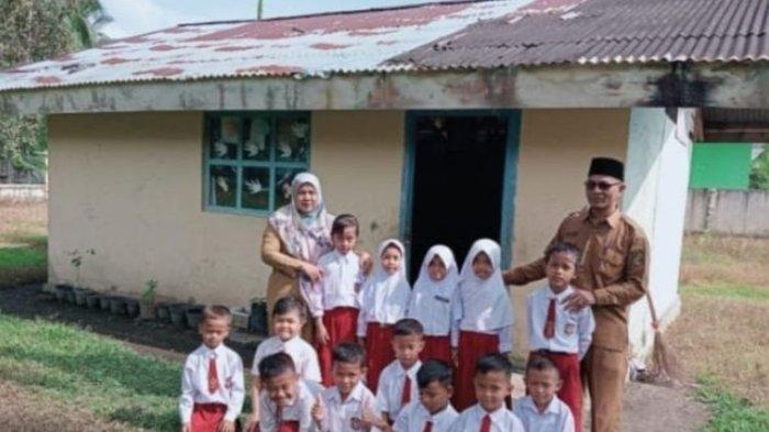 Kepala SDN 002 Tanjung, Kecamatan Koto Kampar Hulu, Kabupaten Kampar, Riau, Apriwardi (kanan) dan seorang guru foto bersama dengan murid yang belajar di ruang kelas bekas WC, Selasa (11/6/2024).