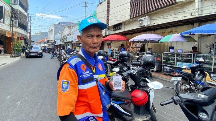 Seorang juru parkir di Jalan ABC, Kota Bandung, menunjukkan barcode untuk pembayaran nontunai, Kamis (10/10/2024).