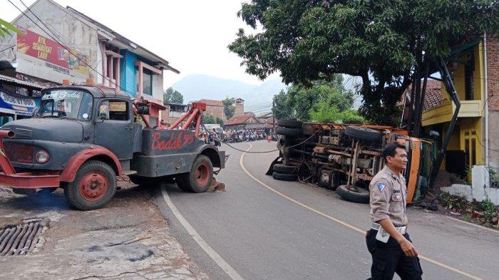 Mobil derek tengah melakukan evakuasi terhadap truk tronton bermuatan pasir bernomor polisi BE 9821 BN yang terguling di Jalan Raya Bandung-Sumedang, Rabu (27/12/2023).
