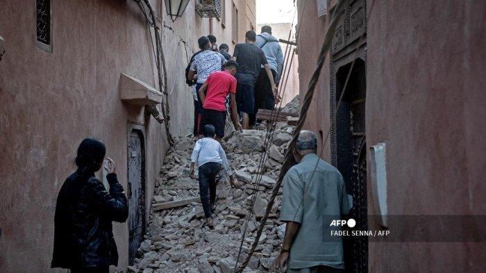 Warga mengungsi melalui reruntuhan di kota tua Marrakesh yang rusak akibat gempa pada 9 September 2023. Gempa bumi dahsyat yang mengguncang Maroko pada akhir 8 September menewaskan lebih dari 600 orang, menurut angka kementerian dalam negeri, membuat warga yang ketakutan meninggalkan rumah mereka di tengah-tengah bencana. malam. FADEL SENNA / AFP
