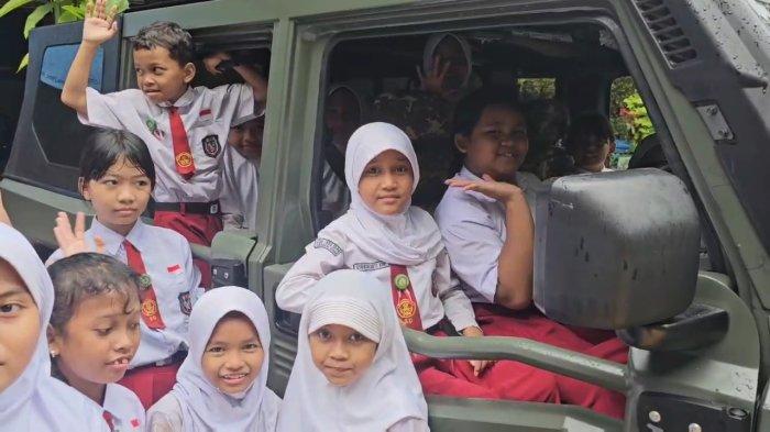 Anak-anak naik mobil tentara Maung buatan Pindad saat digelarnya program Makan Bergizi Gratis di SDN Rawa Badak Utara 01 Pagi, Senin (13/1/2025).