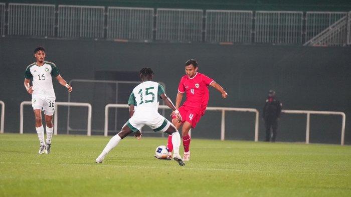 Bek Timnas Indonesia U-23, Komang Teguh Trisnanda berusaha merebut bola dari pemain Arab Saudi.