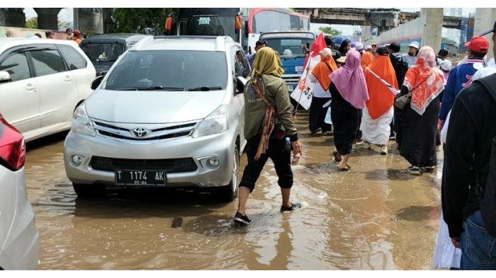 Massa pendukung AMIN berjalan kaki menerjang banjir di Jalan R. E. Martadinata untuk mengarah ke lokasi kampanye di Jakarta International Stadium, Tanjung Priok, Jakarta Utara, Sabtu (10/2/2024).