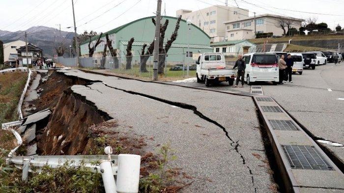 Orang-orang berdiri di dekat retakan besar di trotoar setelah mengungsi ke jalan di kota Wajima, prefektur Ishikawa pada 1 Januari 2024, setelah gempa bumi besar berkekuatan 7,5 melanda wilayah Noto di prefektur Ishikawa pada sore hari.