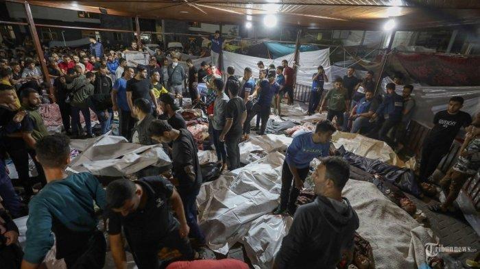 Orang-orang berkumpul di sekitar mayat warga Palestina yang tewas dalam serangan di rumah sakit Ahli Arab di Gaza tengah setelah mereka diangkut ke rumah sakit Al-Shifa, pada 17 Oktober 2023. Serangan di kompleks rumah sakit di Jalur Gaza setidaknya menewaskan korban jiwa yang disalahkan oleh pejabat di wilayah Palestina yang dikuasai Hamas pada 17 Oktober, memicu kecaman dan kemarahan luas. Namun tentara Israel menyalahkan roket yang salah ditembakkan oleh militan di Gaza.