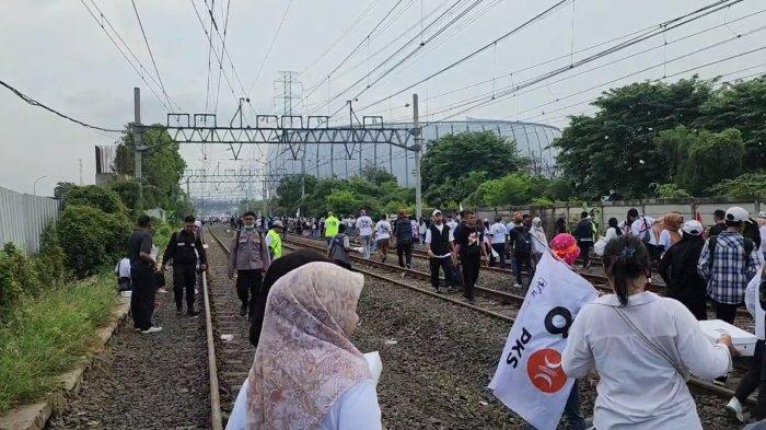 Momen massa pendukung berjalan di atas rel kereta demi datangi kampanye akbar AMIN di Jakarta International Stadium, Tanjung Priok, Jakarta Utara, Sabtu (10/2/2024).