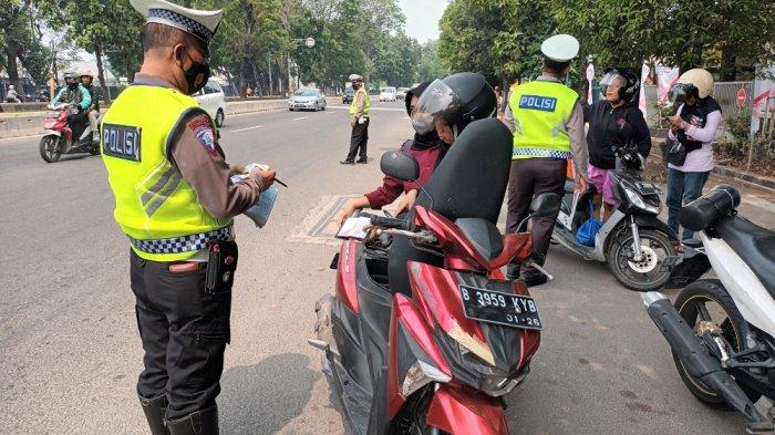 Petugas kepolisian melakukan penindakan penilangan terhadap kendaraan yang belum melakukan uji emisi di Jalan Pemuda, Pulogadung, Jakarta Timur, Jumat (1/8/2023).
