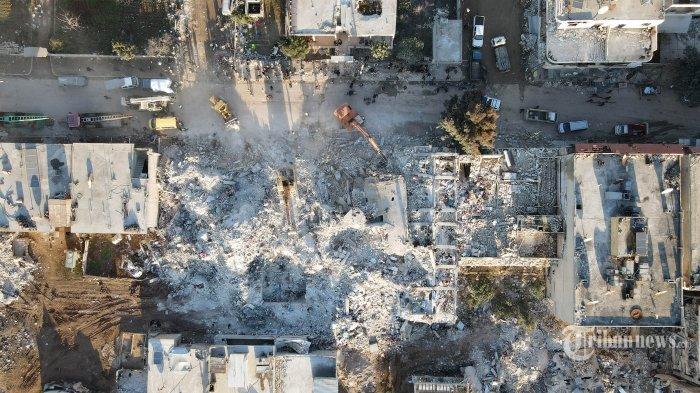 Pemandangan udara menunjukkan petugas penyelamat menggali puing-puing bangunan di kota Jindayris yang dikuasai pemberontak pada 9 Februari 2023, tiga hari setelah gempa mematikan yang melanda Turki dan Suriah. - Gempa berkekuatan 7,8 pada awal 6 Februari telah menewaskan lebih dari 17.000 orang di Turki dan Suriah yang dilanda perang, menurut pejabat dan petugas medis di kedua negara, meratakan seluruh lingkungan.