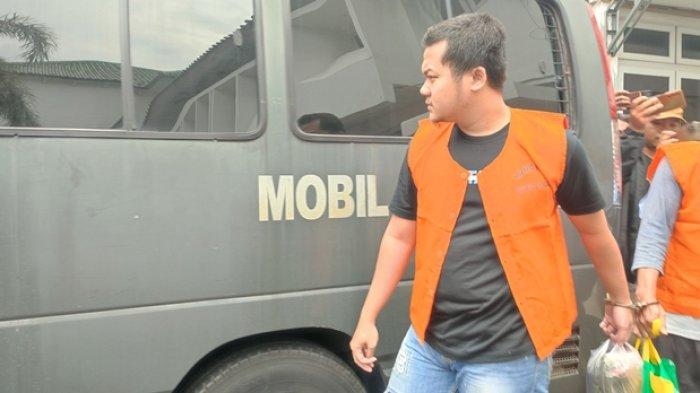 HINDARI KAMERA - Ade Kurniawan tampak berusaha menutupi wajahnya saat diserahkan ke Jaksa di Kantor Kejaksaan Negeri (Kejari) Semarang, Kamis (19/6/2025).