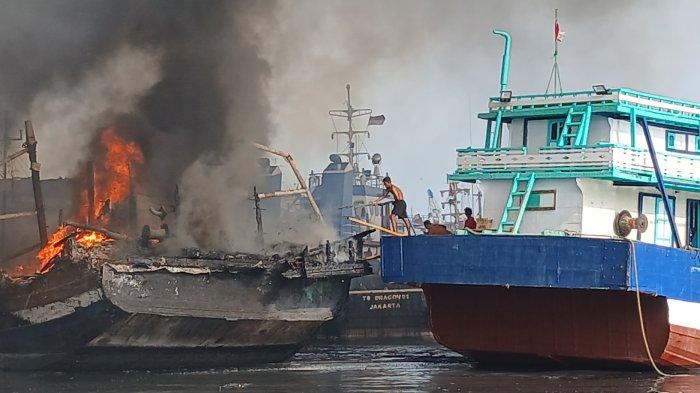 Seorang nelayan atau anak buah kapal (ABK) hanya memakai celana pendek melindungi kapal bosnya dari kapal yang terbakar di area Dok dan Galangan Kapal PT Pantai Mulia Semesta Tegal, Jumat (27/12/2024).