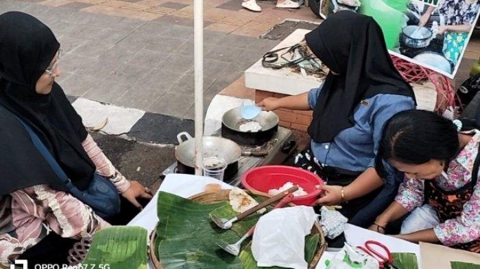Elvina Kristina (berbaju biru) saat membuat intip ketan pesanan pembeli