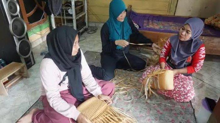Ibu rumah tangga di Desa Sugihan, Kecamatan Winong, Pati, memanfaatkan waktu luang dengan menganyam tas sembari bercerita bersama penganyam lainnya, Jumat (6/10/2023).
