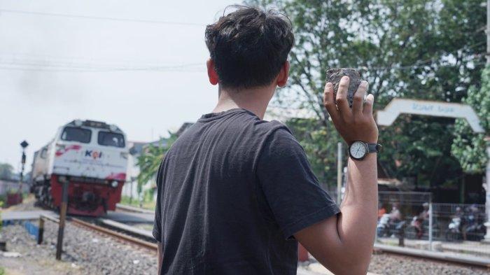 Ilustrasi seseorang saat hendak melakukan pelemparan batu ke kereta api yang tengah melintas. (Dok. Humas KAI Daop 4 Semarang)