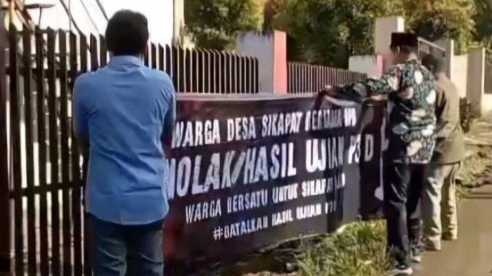 PASANG SPANDUK: Sejumlah warga Desa Sikapat, Kecamatan Sumbang, Kabupaten Banyumas, saat memasang spanduk yang menuliskan dugaan kecurangan yang mencederai integritas tahapan ujian perangkat desa (P3D), Minggu (18/5/2025). Proses seleksi perangkat desa menjadi sorotan tajam.