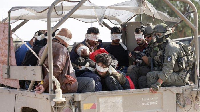 Tentara Israel memindahkan warga Palestina yang ditahan keluar dari Jalur Gaza pada 21 November 2023, di tengah pertempuran yang sedang berlangsung antara Israel dan gerakan Hamas Palestina.