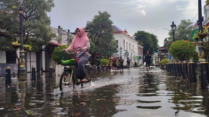 Warga menerabas banjir di kawasan Kota Lama Semarang, Kamis (14/3/2024)