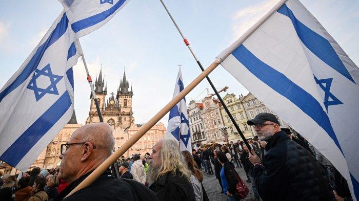 Para pengunjuk rasa mengibarkan bendera negara Israel saat mereka mengikuti unjuk rasa solidaritas terhadap Israel dan masyarakat yang disandera dalam serangan Hamas di Praha, Republik Ceko pada 1 November 2023.