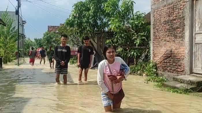 KEBANJIRAN - Warga melintas di Dukuh Pidodo, Desa Karangrejo, Kecamatan Bonang, Kabupaten Demak, Jawa Tengah, yang kebanjiran akibat tanggul jebol dan limpasan air dari Sungai Tuntang, Minggu (18/5/2025).