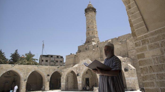Dokumentasi, seorang pria Palestina memegang salinan Al-Quran, kitab suci umat Islam, pada hari pertama puasa di bulan suci Ramadhan, di masjid al-Omari di Kota Gaza, pada 27 Mei 2017.