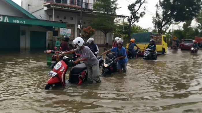 Para pengendara menuntun sepeda motor menerjang banjir di Jalan Raya Kudus-Purwodadi karena mati mesin, Minggu (5/3/2023).