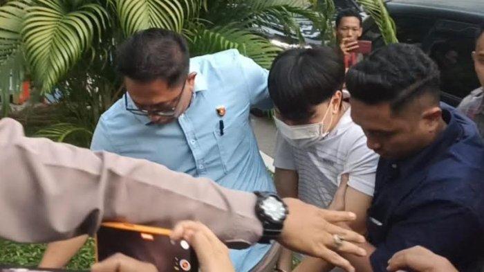 Polisi menggelandang pengusaha berinisial IV setelah memaksa siswa di SMAK Gloria 2 Surabaya untuk sujud dan menggonggong. IV tiba di Polrestabes Surabaya, Kamis (14/11/2024).