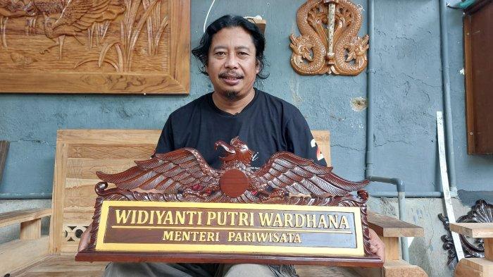 SENI PAHAT KAYU - Pemahat seni kayu difabel, Mohak asal Desa Peh Kulon Kecamatan Papar Kabupaten Kediri menunjukkan pesanan papan nama untuk Menteri Pariwisata, Widiyanti Putri, Jumat (31/1/2025). Mohak juga aktif sebagai Ketua Disabilitas Bidang UMKM di Kabupaten Kediri bersama teman-teman difabel lainnya berusaha menggerakkan roda ekonomi dengan memproduksi berbagai produk kerajinan
