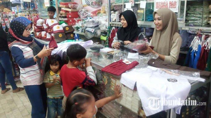 Foto hanya ilustrasi. Pegawai Toko Lancar Jaya melayani orang tua siswa yang mencari seragam baru