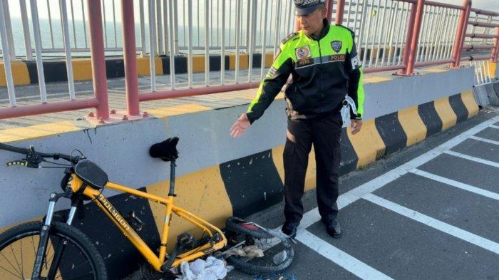 KORBAN TABRAK LARI : Kondisi sepeda angin jenis MTB berwarna kuning milik korban Taufik Hidayat (57), warga Jalan Rambutan, Desa Banyuajuh, Kecamatan Kamal, Bangkalan setelah diserempet kendaraan pikap misterius di pinggir jalur mobil Jembatan Suramadu KM 3400 tujuan Surabaya, Minggu (13/7/2025). Korban meregang nyawa di lokasi kejadian