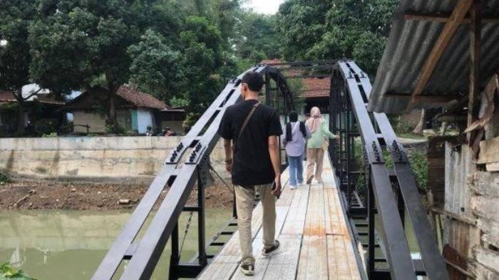 Salah seorang warga terlihat melintas di atas jembatan besi yang dibangun oleh keluarga Sunardi, Selasa (19/11/2024). Sunardi membangun jembatan ini setelah akses jalan menuju dan dari rumahnya ditutup oleh tetangganya.