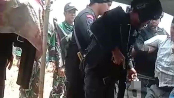 BAWA SENPI: Personel Brimob pengamanan pilkades memegang sepucuk senjata api (senpi) yang diamankan dari tubuh seorang pria mengenakan peci hitam di sekitar TPS Pilkades Durin Barat, Kecamatan Konang, Rabu (25/10/2023).
