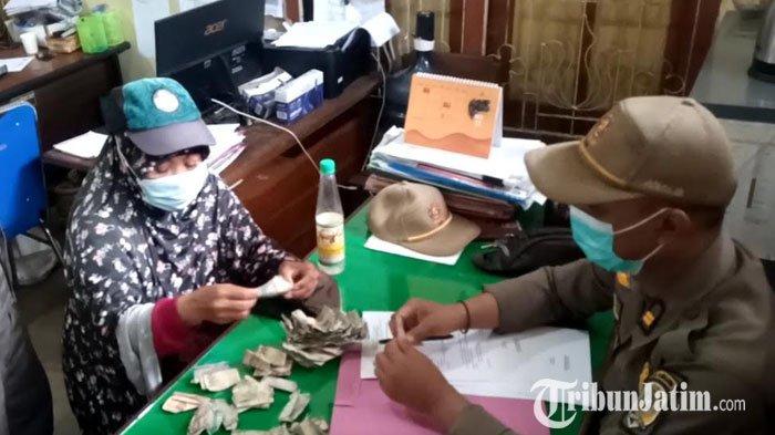 Seorang PPKS menghitung uang hasilnya mengemis selama 2 jam