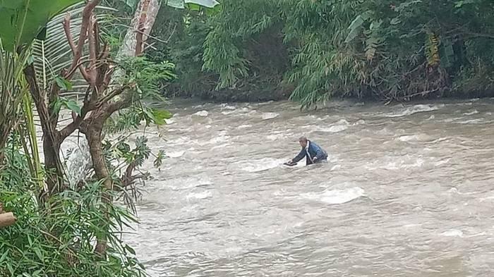 Seorang guru di Kabupaten Cianjur, Jawa Barat, tengah menyusuri aliran sungai Cikondang, Kecamatan Campaka akibat jembatan putus.