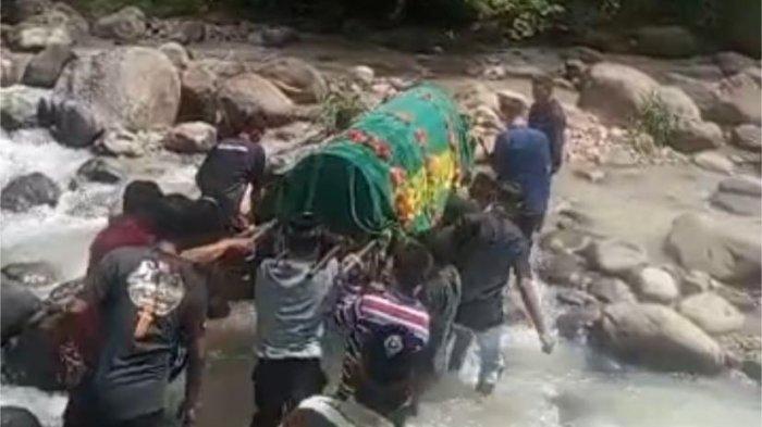 LEWAT SUNGAI - Rombongan pembawa keranda jenazah melintasi sungai di perbatasan Desa Wates dengan Desa Tugurejo Kecamatan Slahung Kabupaten Ponorogo, Jatim, Sabtu (19/4/2025). Viral, sekelompok warga di Ponorogo mengantarkan keranda jenazah melewati sungai.