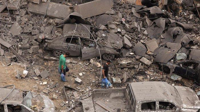 Warga Palestina berjalan melewati puing-puing di lingkungan yang dibombardir setelah serangan udara Israel semalaman di kamp pengungsi Shati di Kota Gaza pada awal 9 Oktober 2023. PBB mengatakan lebih dari 260.000 orang meninggalkan rumah mereka di jalur Gaza ketika pemboman besar-besaran Israel terus menghantam Palestina.