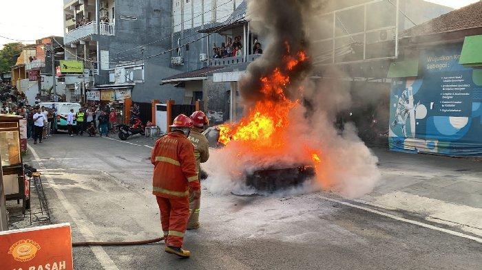 Petugas PMK Kota Malang saat memadamkan kebakaran mobil sedan yang terjadi di Jalan Watu Gong Kelurahan Ketawanggede Kecamatan Lowokwaru Kota Malang, Senin (11/12/2023).