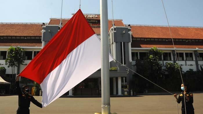 Petugas sedang mengibarkan bendera merah putih di Balai Kota Surabaya, 2021.