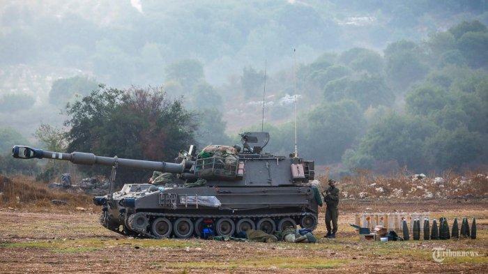 Seorang tentara Israel berjaga di samping meriam artileri di lokasi yang dirahasiakan di Israel utara yang berbatasan dengan Lebanon pada 8 Oktober 2023. Sebanyak 26 tentara Israel tewas.