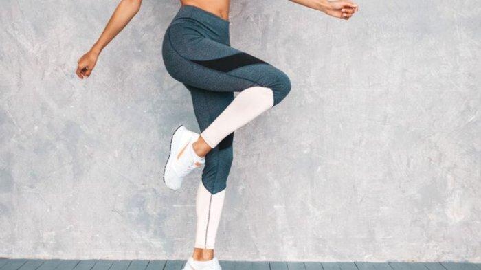 Female jumping in studio near gray wall