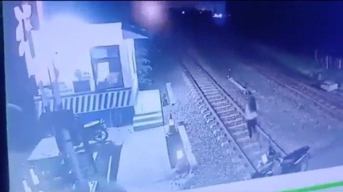 Seorang perempuan terlihat turun dari sepeda motor dan berjalan di atas rel yang bakal dilewati kereta api, Rabu (15/11/2023) malam sekitar pukul 22:06 WIB