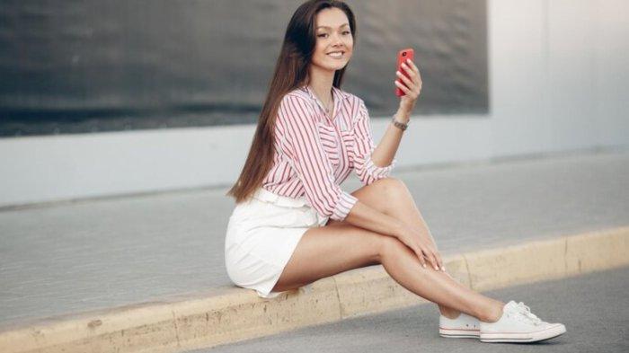 Young smiling woman with mobile phone outdoors