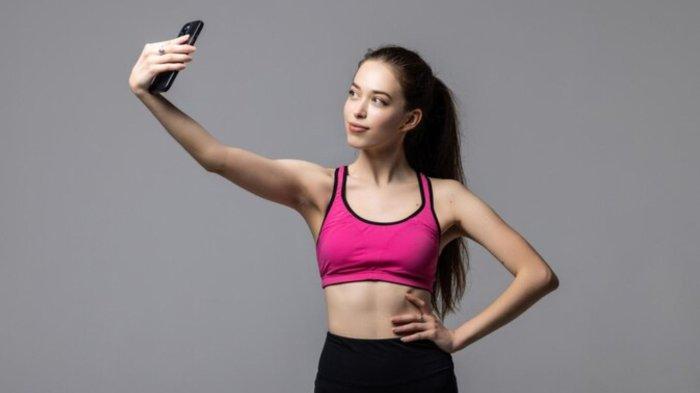 Beautiful fitness woman making selfie photo on a white